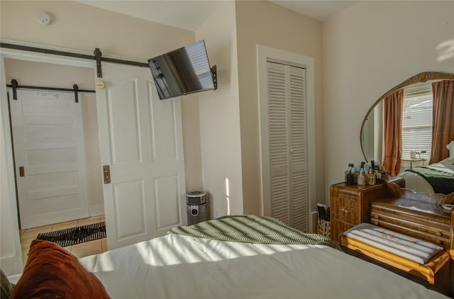 bedroom featuring tile patterned flooring, a closet, and a barn door