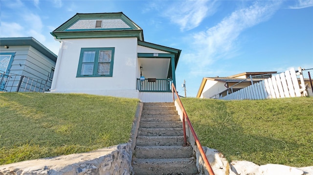 view of front of house with stucco siding, fence, and a front yard