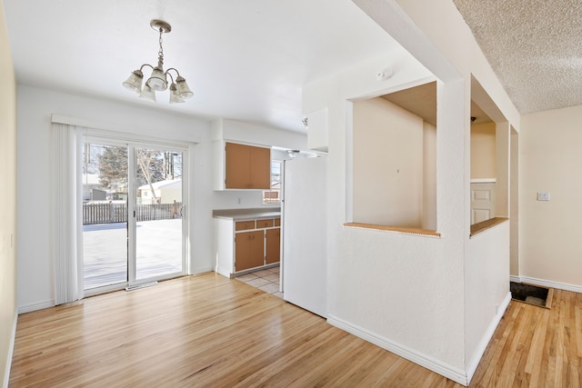 kitchen featuring hanging light fixtures, a notable chandelier, light wood-type flooring, and white refrigerator