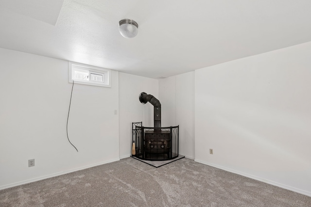 basement featuring a wood stove and light colored carpet