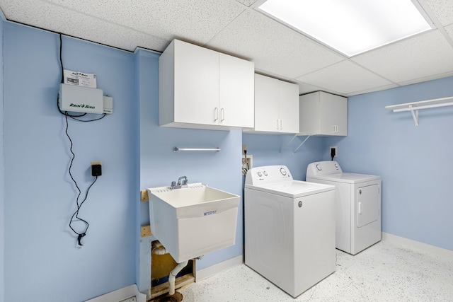 clothes washing area featuring cabinets, sink, and washing machine and clothes dryer