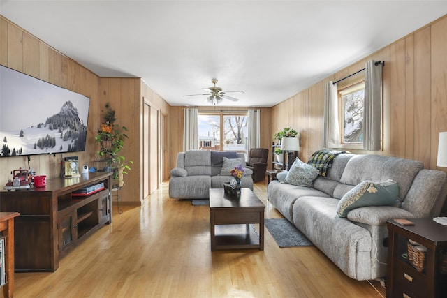 living room featuring ceiling fan, wooden walls, and light hardwood / wood-style floors