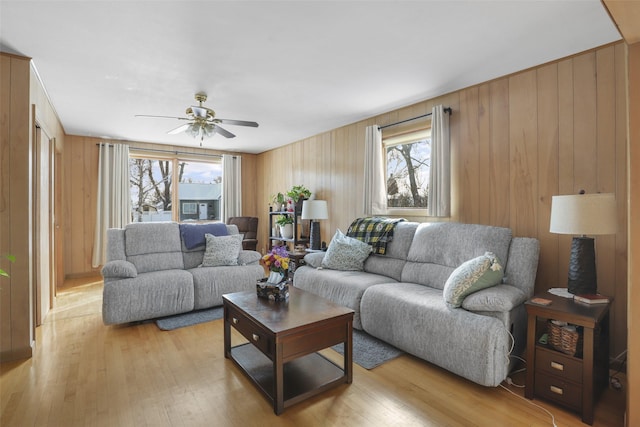 living room featuring light hardwood / wood-style floors, ceiling fan, and wood walls