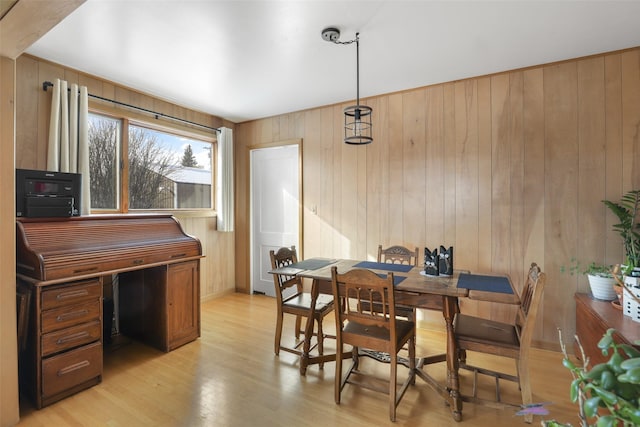 dining room with wooden walls and light hardwood / wood-style floors