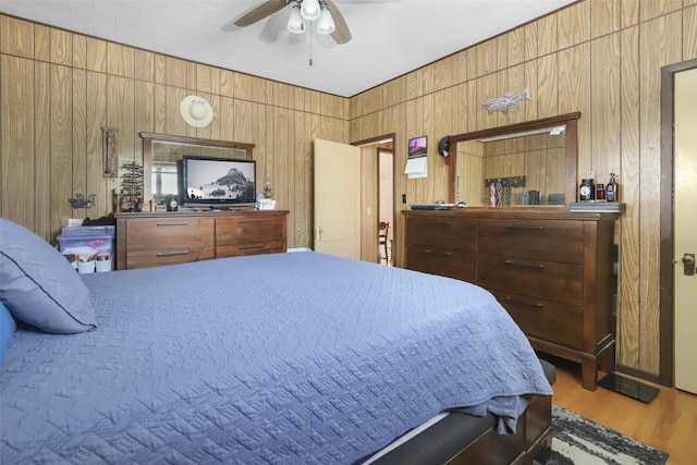 bedroom with hardwood / wood-style flooring, ceiling fan, and wood walls