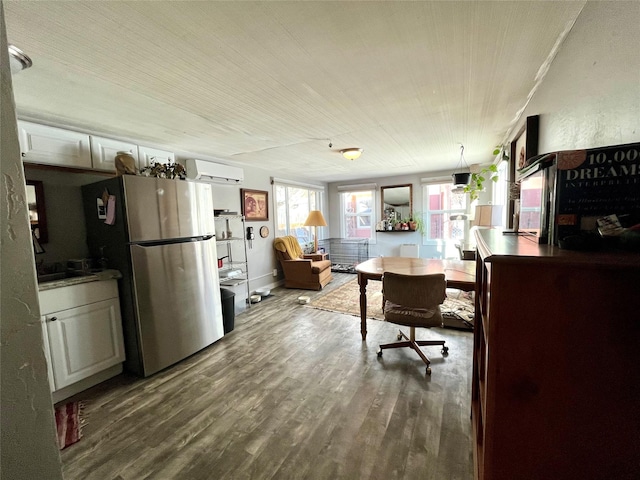 kitchen featuring hardwood / wood-style flooring, a wall mounted air conditioner, and stainless steel fridge