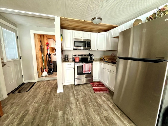 kitchen featuring light stone counters, wood-type flooring, stainless steel appliances, and white cabinets