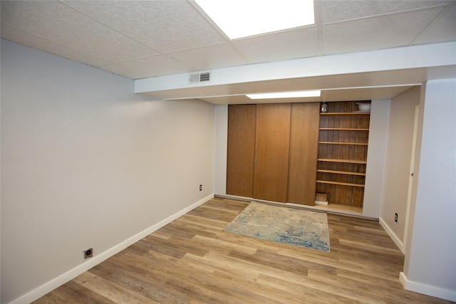 basement with wood-type flooring and a paneled ceiling