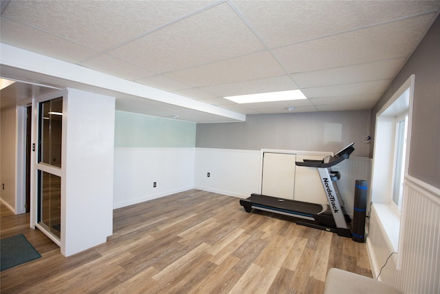 exercise room with light hardwood / wood-style floors and a drop ceiling