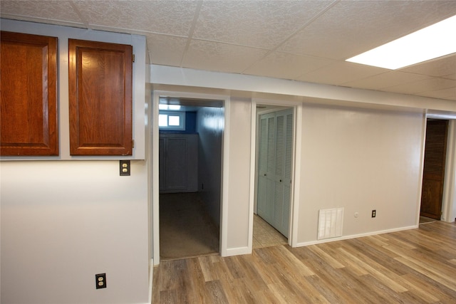 empty room with a drop ceiling and light hardwood / wood-style flooring