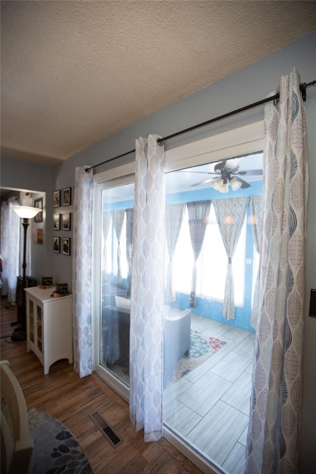 entryway featuring ceiling fan, wood-type flooring, and a textured ceiling