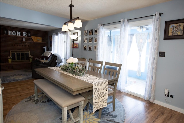 dining area with dark wood-type flooring, a fireplace, a textured ceiling, and a wealth of natural light