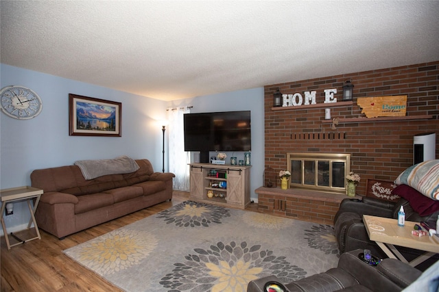 living room with wood-type flooring, a textured ceiling, and a fireplace