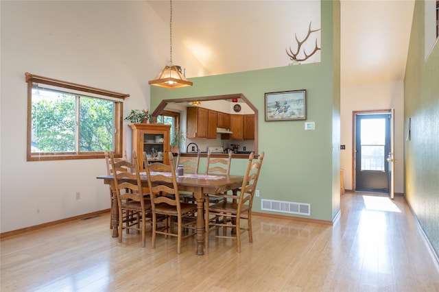 dining room with high vaulted ceiling and light wood-type flooring