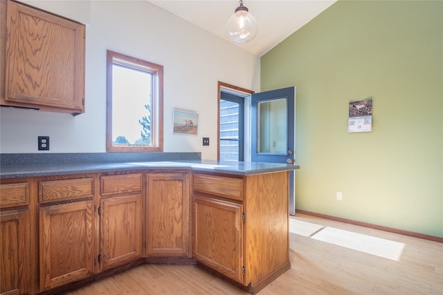 kitchen featuring vaulted ceiling, kitchen peninsula, light hardwood / wood-style floors, and decorative light fixtures