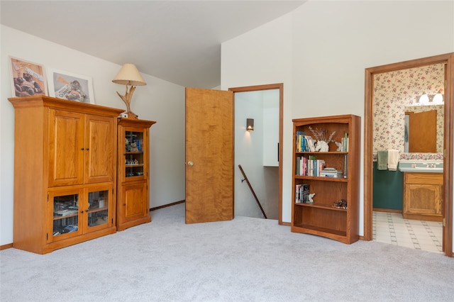 interior space with lofted ceiling, sink, and light carpet