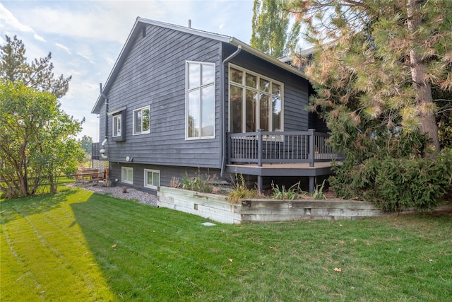 rear view of house with a wooden deck and a lawn