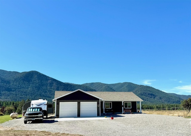 ranch-style home with a garage, gravel driveway, and a mountain view