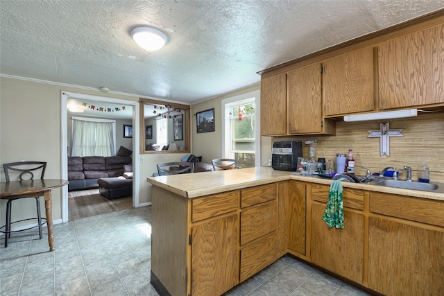 kitchen featuring sink, ornamental molding, kitchen peninsula, and a textured ceiling