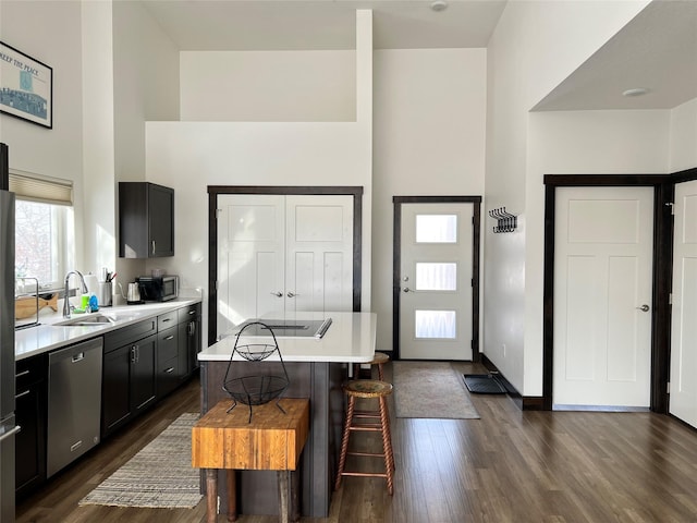 kitchen with sink, a center island, dark hardwood / wood-style floors, dishwasher, and a high ceiling