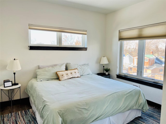 bedroom with multiple windows and dark hardwood / wood-style floors