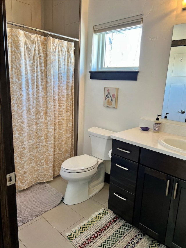 bathroom featuring tile patterned flooring, vanity, toilet, and walk in shower