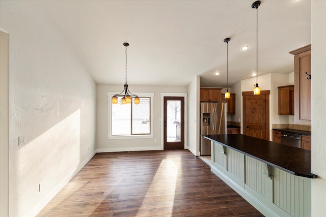 interior space featuring stainless steel appliances, dark wood-type flooring, pendant lighting, and a kitchen breakfast bar