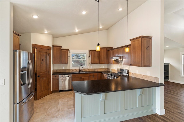 kitchen with pendant lighting, sink, a kitchen bar, kitchen peninsula, and stainless steel appliances