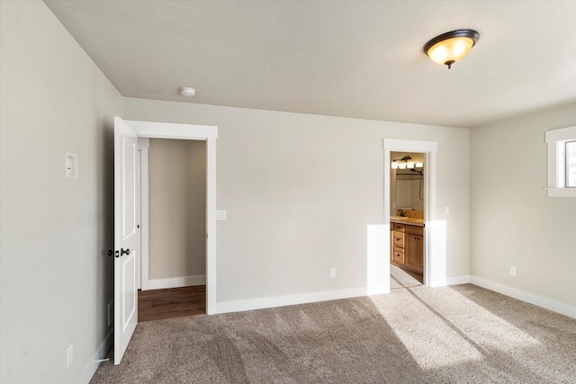 unfurnished bedroom featuring ensuite bathroom and light carpet