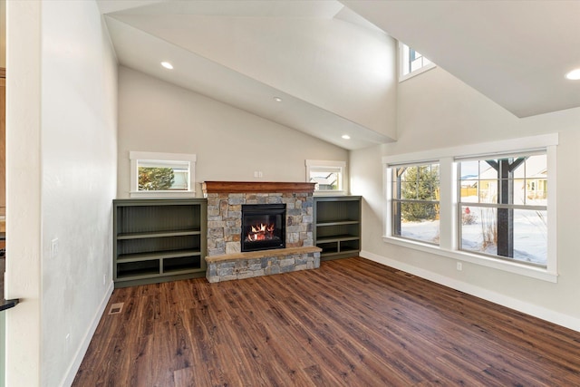 unfurnished living room with a stone fireplace, a healthy amount of sunlight, high vaulted ceiling, and dark hardwood / wood-style floors