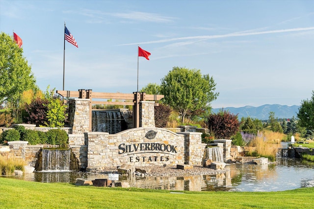 community sign featuring a lawn and a water and mountain view