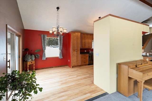 kitchen with lofted ceiling, an inviting chandelier, hanging light fixtures, black dishwasher, and light hardwood / wood-style floors