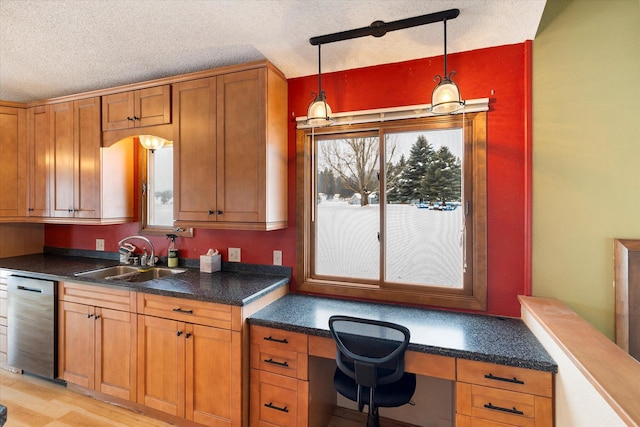 kitchen featuring sink, dishwasher, built in desk, a textured ceiling, and decorative light fixtures