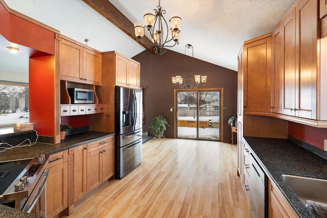 50 Stonecrest Dr, Kalispell, MT 59901 - kitchen featuring stainless steel appliances, a chandelier, light wood-style flooring, vaulted ceiling, and pendant lighting