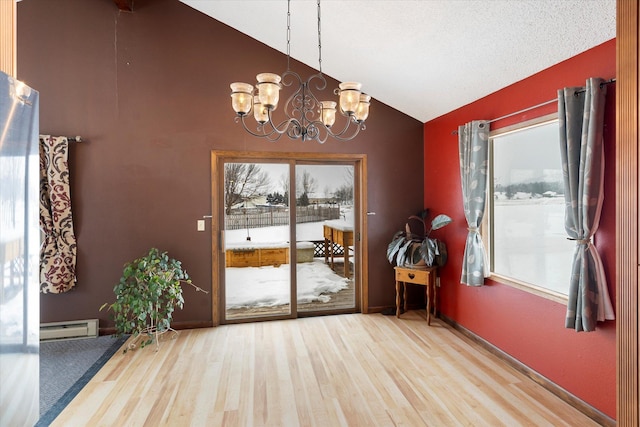 doorway with vaulted ceiling, a baseboard heating unit, a wealth of natural light, and a notable chandelier