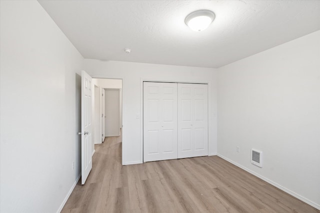 unfurnished bedroom with a closet, a textured ceiling, and light wood-type flooring