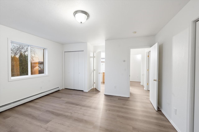 unfurnished bedroom featuring a baseboard radiator, a closet, and light hardwood / wood-style flooring