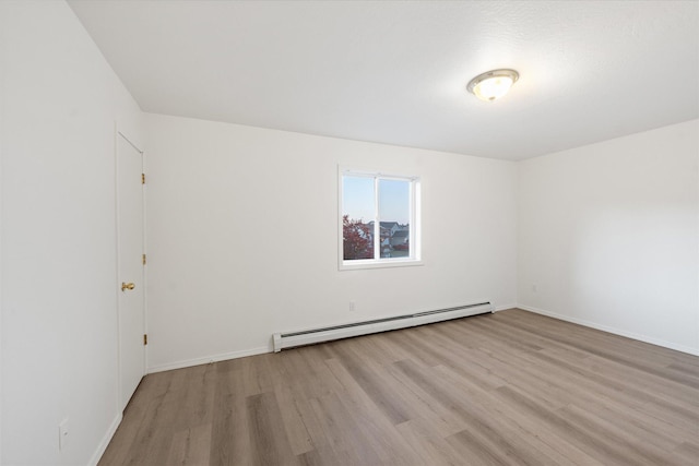 spare room featuring a baseboard heating unit and light wood-type flooring