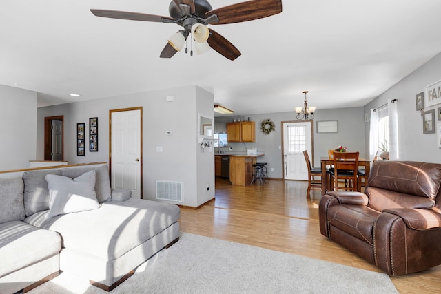 living room featuring ceiling fan with notable chandelier and light hardwood / wood-style floors