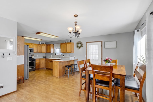 dining area with sink, a chandelier, and light wood-type flooring