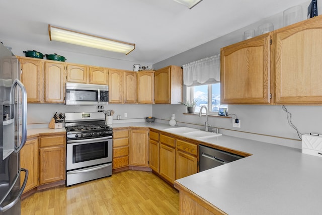 kitchen featuring appliances with stainless steel finishes, sink, light brown cabinets, and light hardwood / wood-style floors