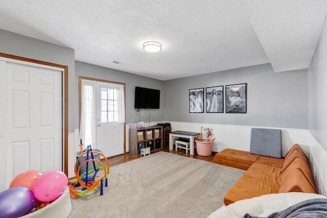 playroom featuring wood-type flooring and a textured ceiling