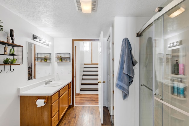 bathroom featuring hardwood / wood-style flooring, vanity, a textured ceiling, and a shower with shower door