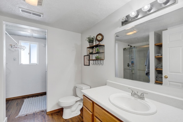 bathroom with hardwood / wood-style floors, vanity, walk in shower, toilet, and a textured ceiling