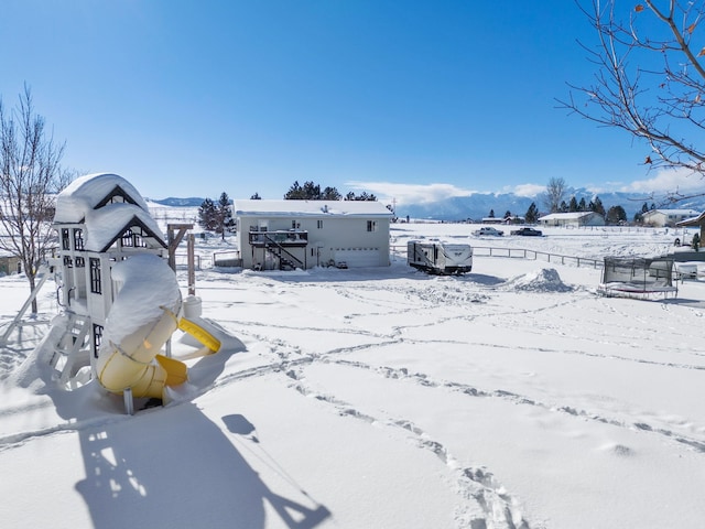 yard covered in snow featuring a mountain view and a playground