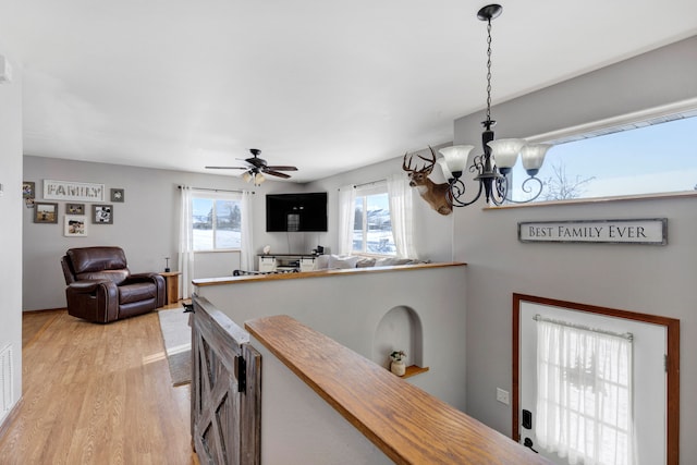 dining space with ceiling fan with notable chandelier and light wood-type flooring