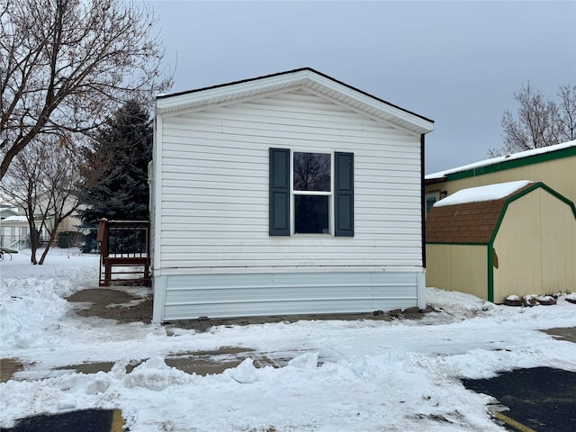 view of snow covered exterior with a shed