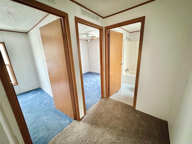 hallway featuring ornamental molding, carpet floors, and a textured ceiling