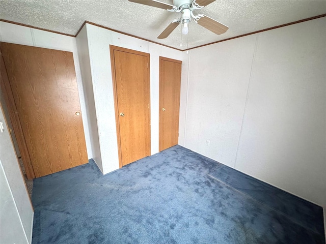 unfurnished bedroom with ceiling fan, ornamental molding, a textured ceiling, and dark colored carpet