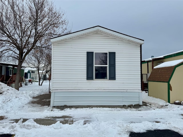 view of snow covered exterior with a storage shed